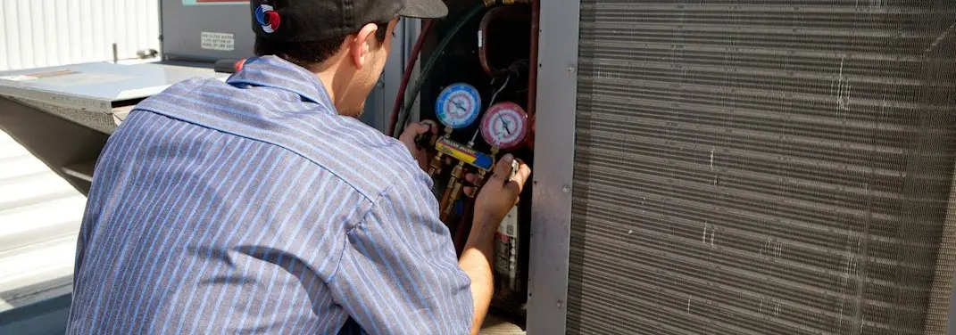 HVAC technician servicing a condenser unit in Seaford